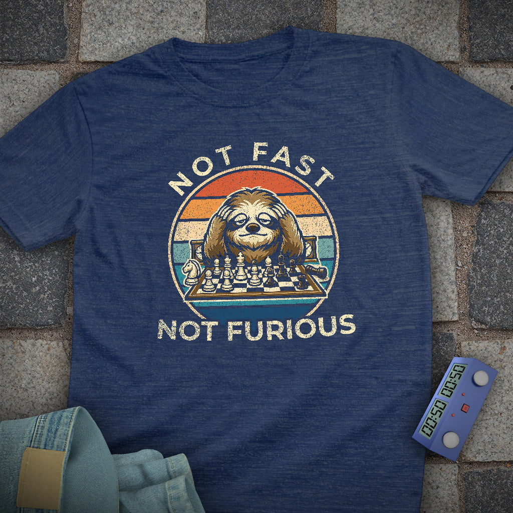 Blue t-shirt with a graphic of a sloth playing chess and 'Not Fast Not Furious' text on a stone surface.